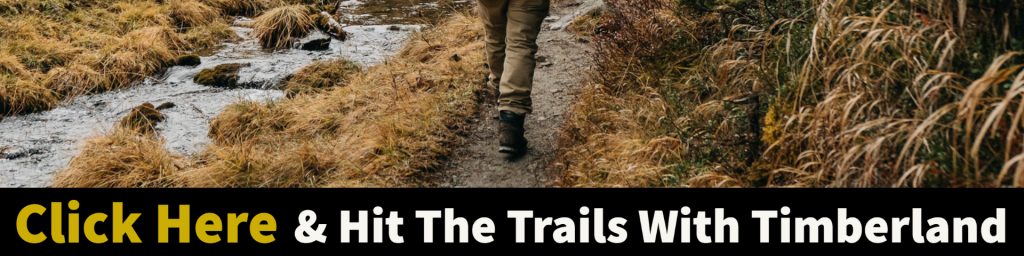 Person walking along a wet gravel trail next to a small creek.  Words across the bottom Click Here and hit the trails with timberland. 