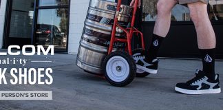 man wearing Volcom work shoes pushing a cart with a barrel